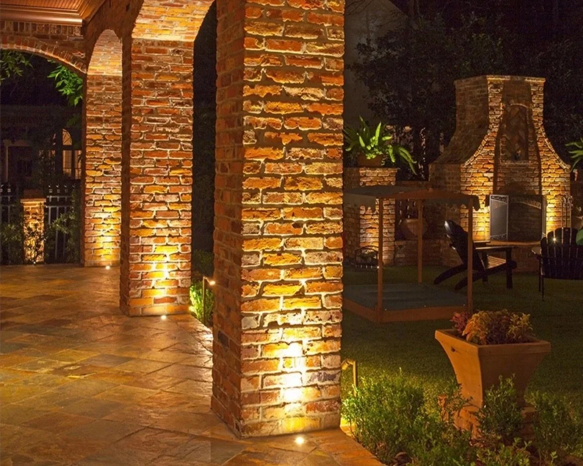 Warm uplighting on brick columns and outdoor living area at night