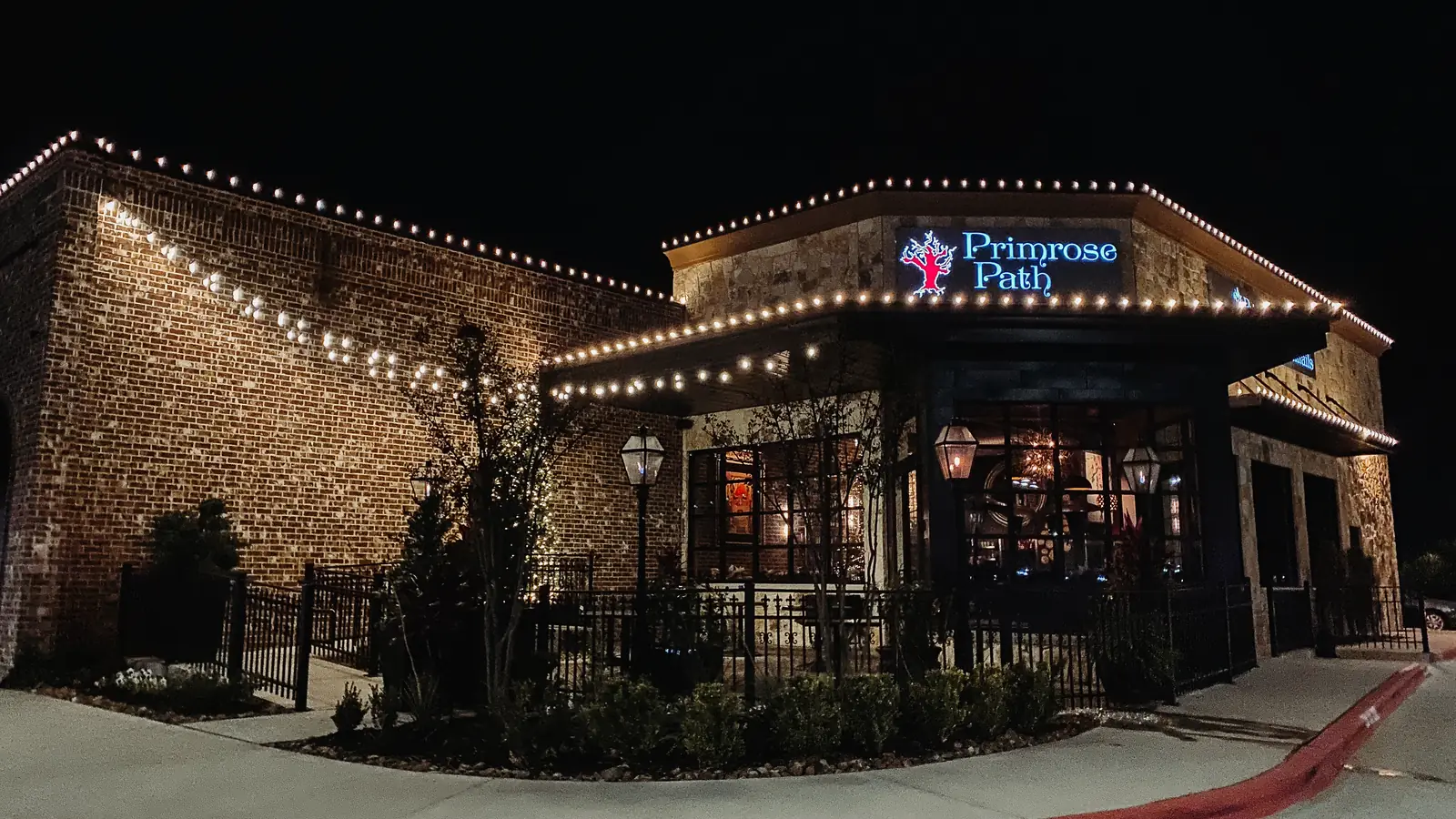 Storefront with warm white holiday roofline and entry lighting at night