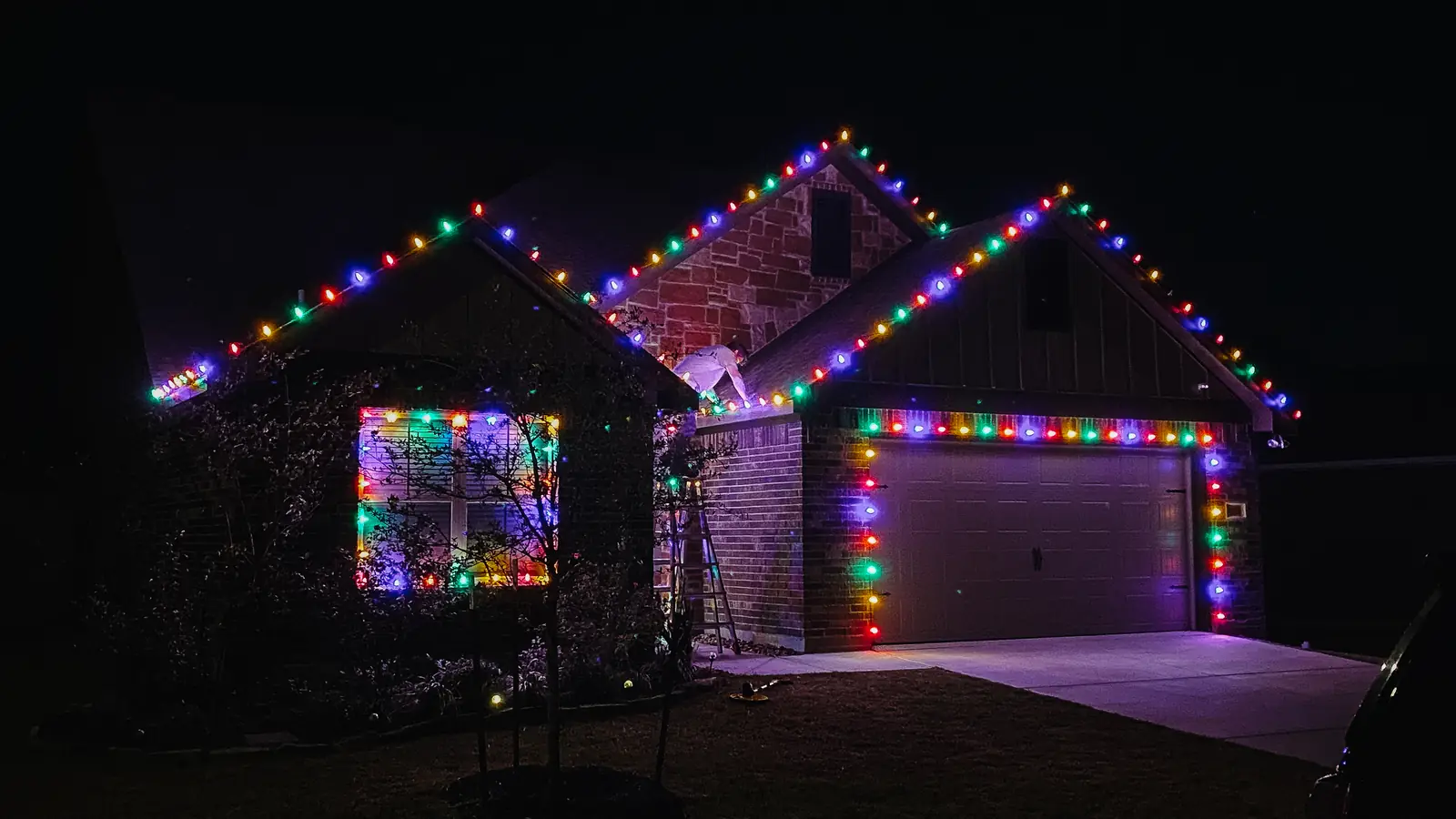 Multicolor Christmas roofline lights on a brick home