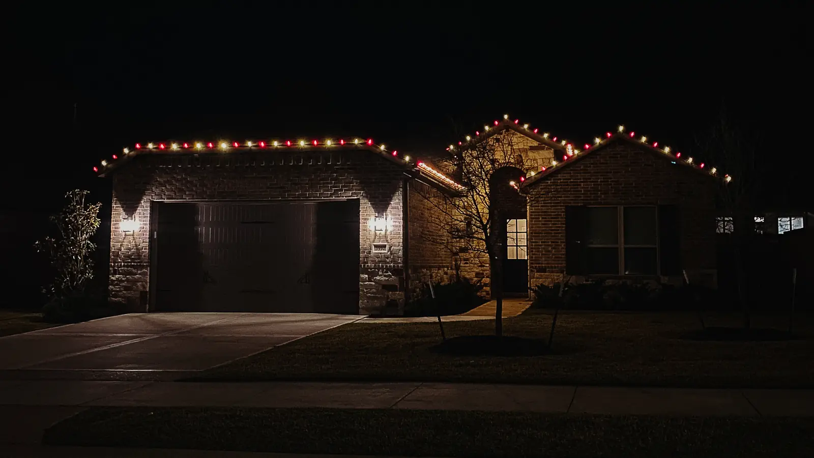 Red and warm white Christmas lights on a brick home and front entry
