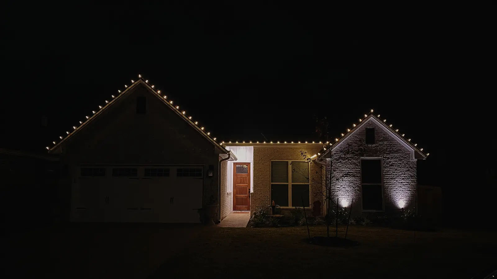 Warm white Christmas lights on a single-story brick home